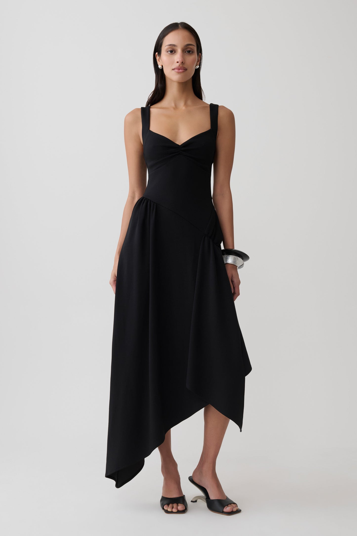 Woman wearing a black asymmetric hem midi dress.
