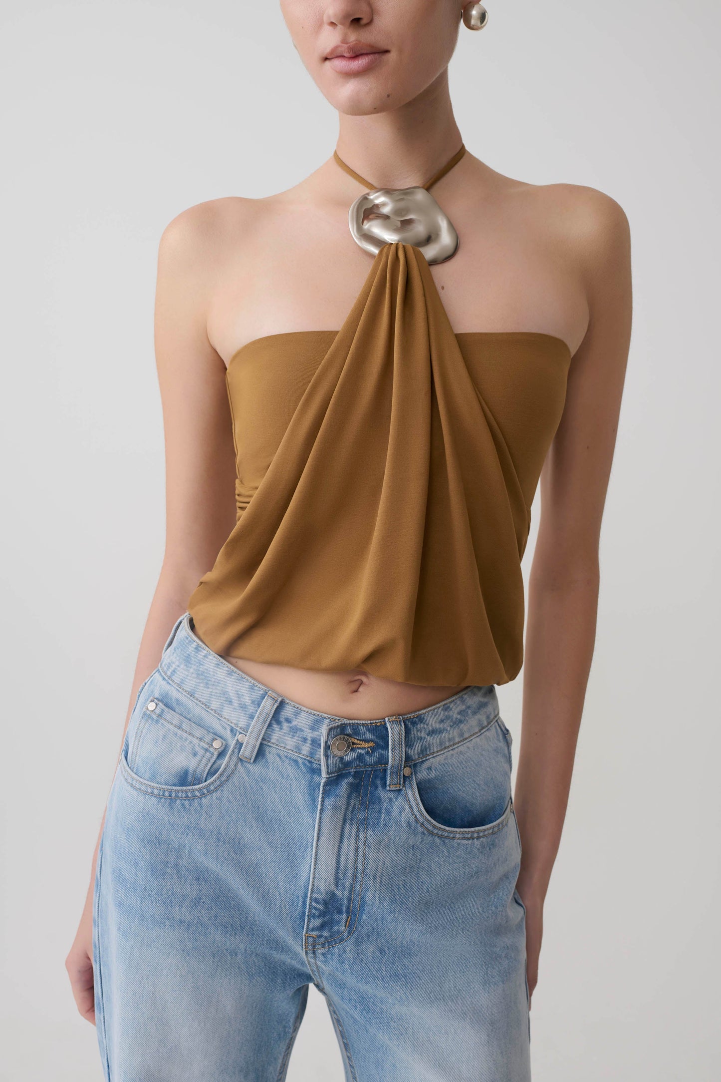 Woman wearing a caramel halter top with hardware.