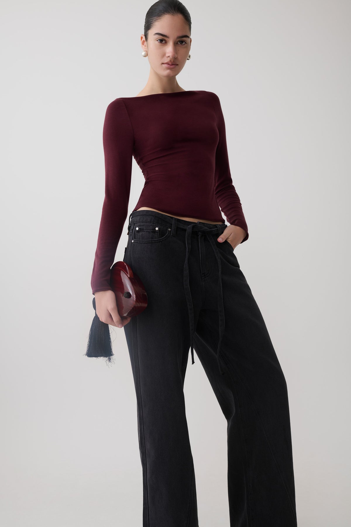 Woman wearing a burgundy long sleeve sheer top.