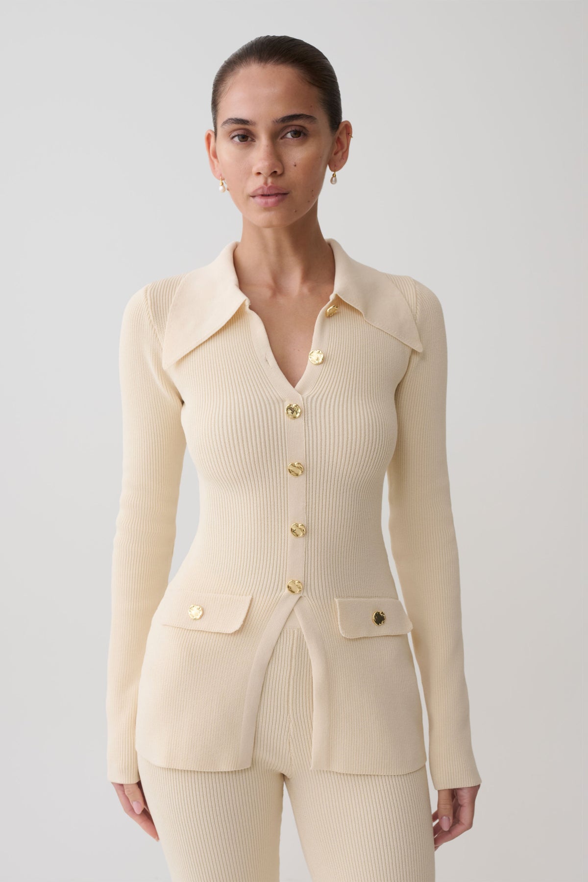 Woman wearing a white ribbed long sleeve longline top.