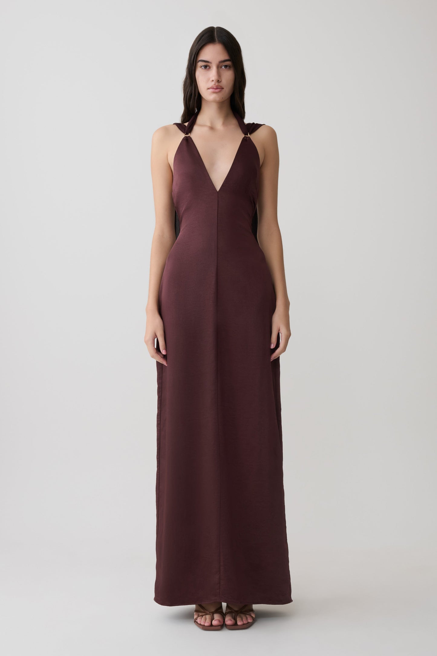Woman wearing a brown draped shoulders satin maxi dress.