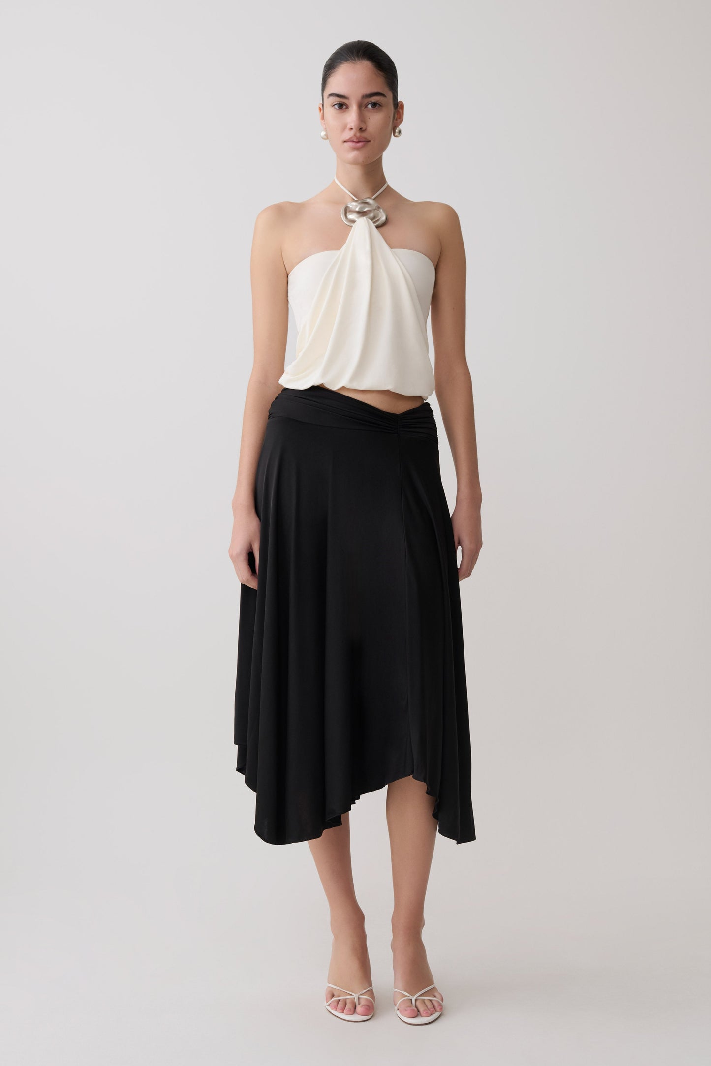 Woman wearing a white halter top and black slinky midi skirt.