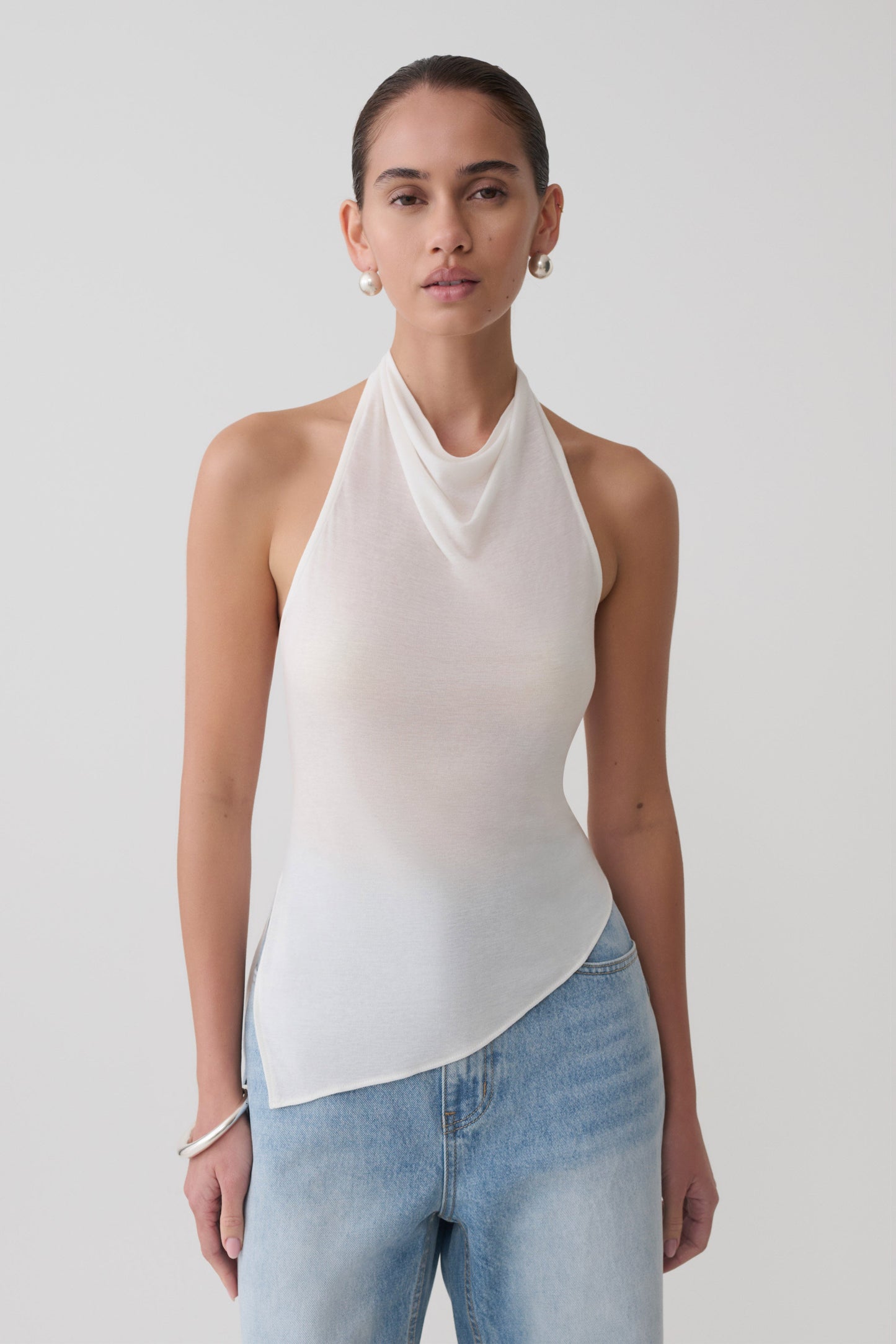 Woman wearing a white relaxed sheer halter top.