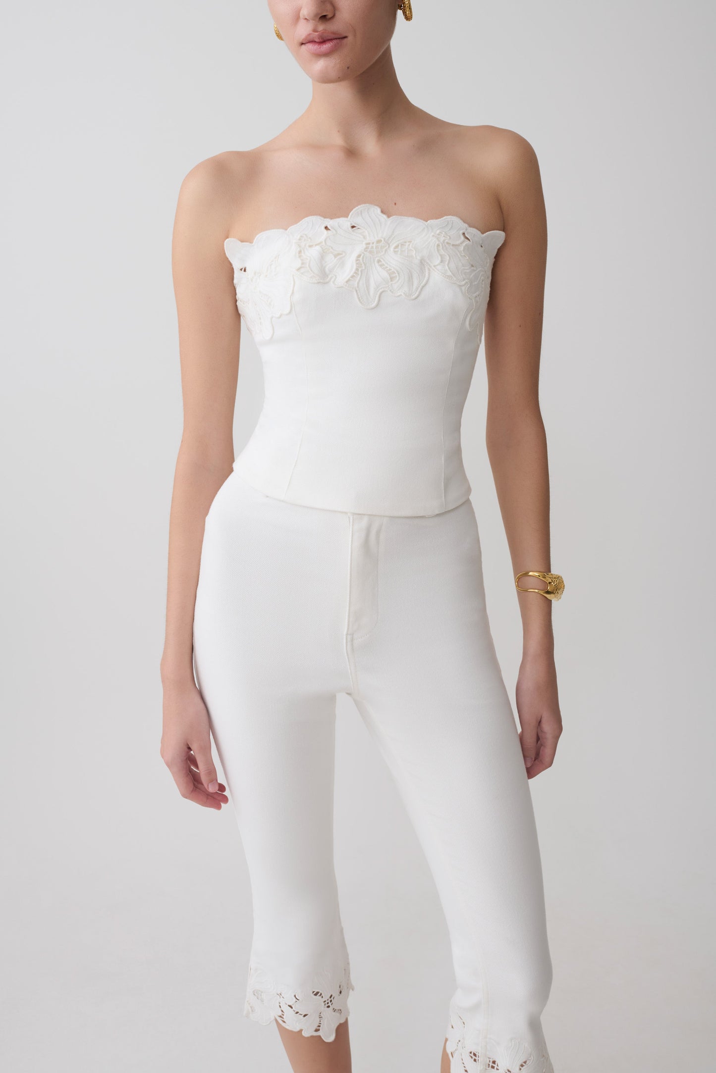 Woman wearing a white embroidery strapless denim top.