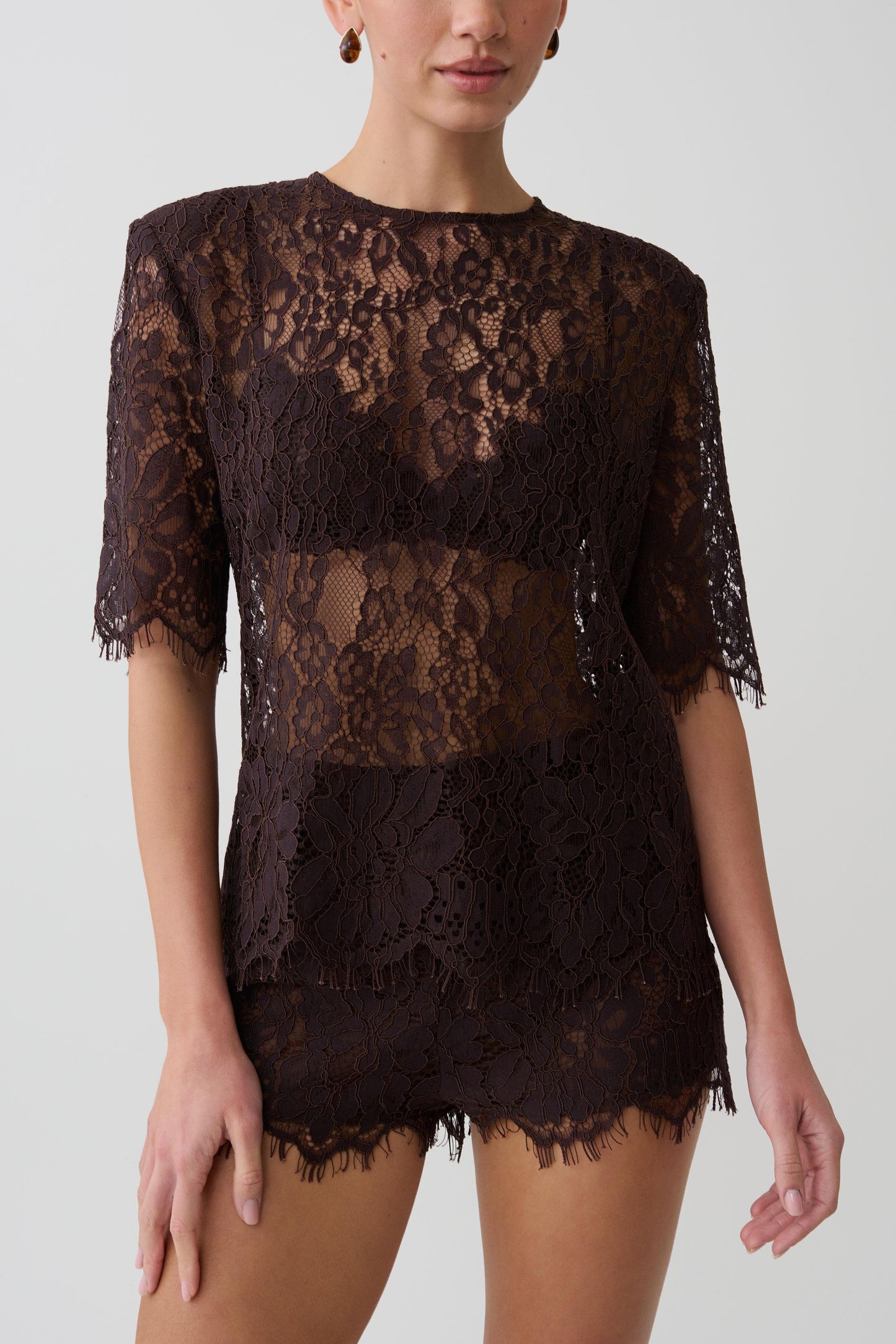Woman wearing dark brown shoulder pad short sleeve lace top with matching mini shorts.
