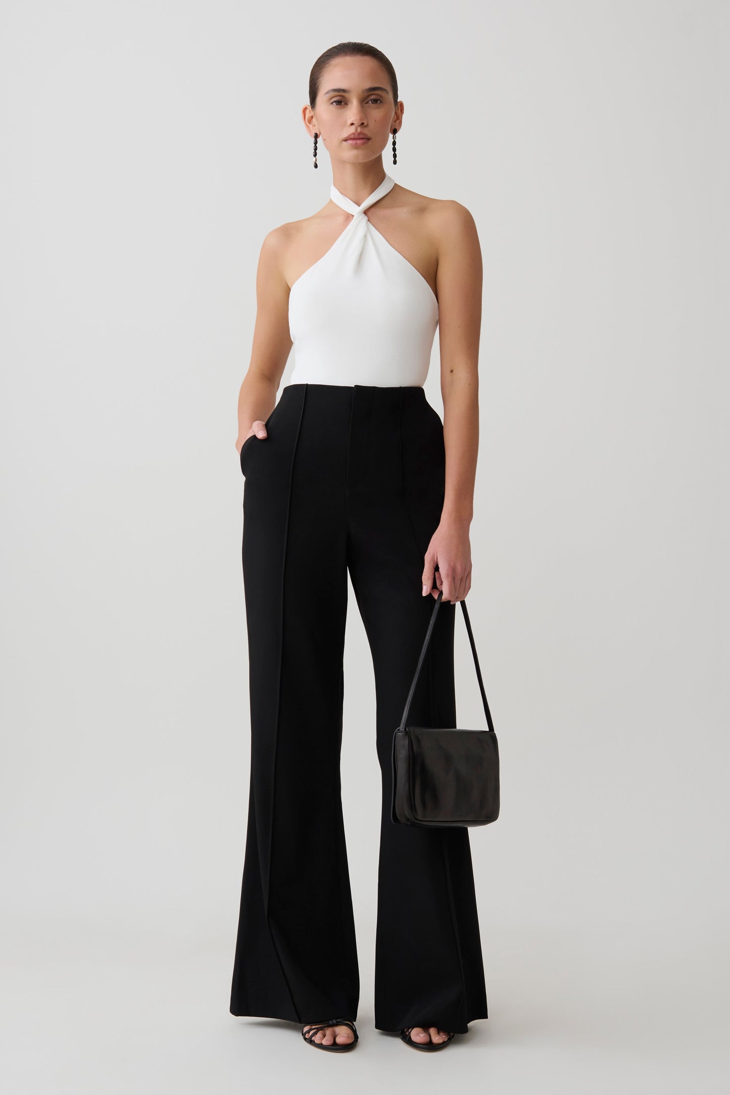 Woman wearing a white twisted neck bodysuit.