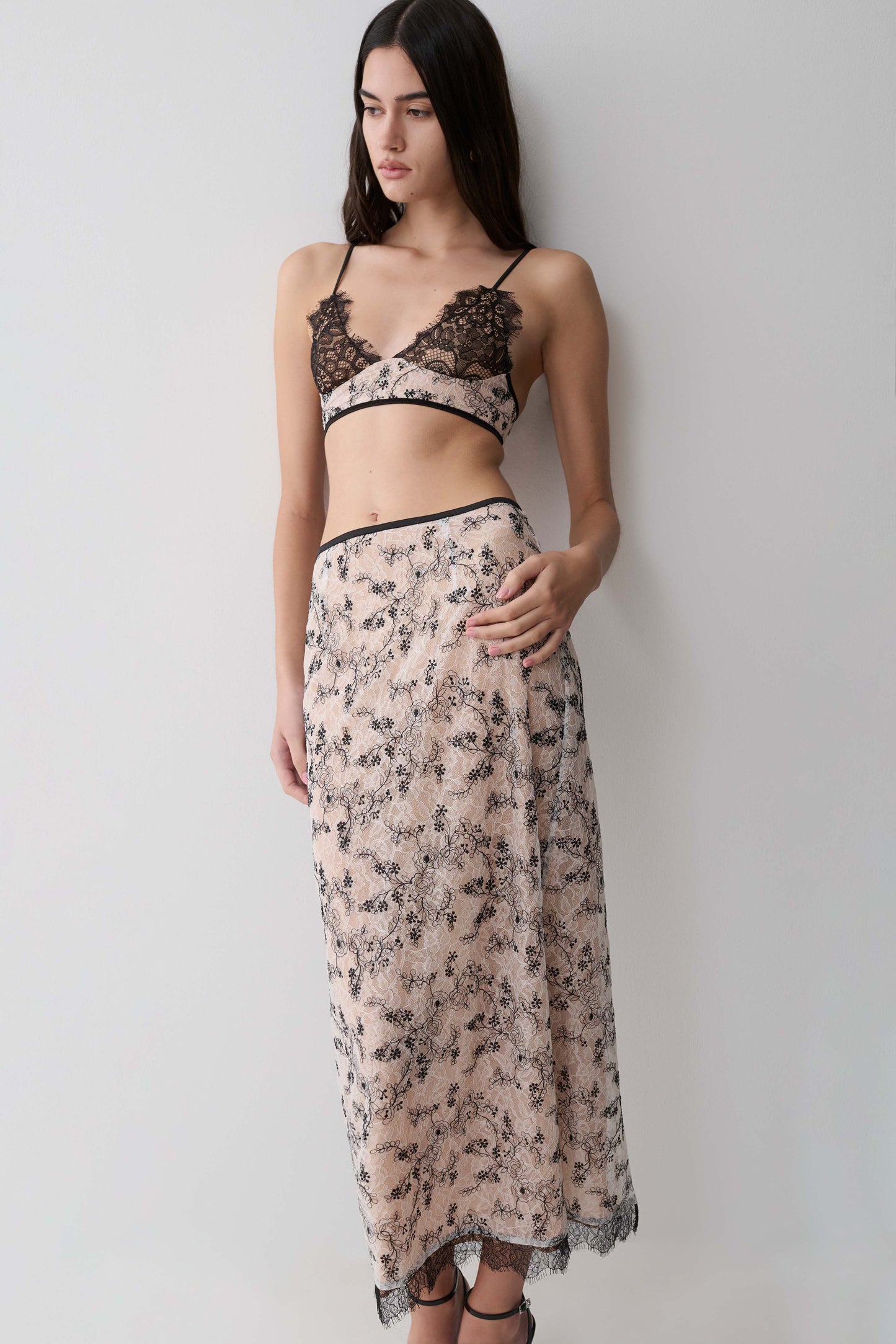 Woman wearing a a nude lace pencil midi skirt.