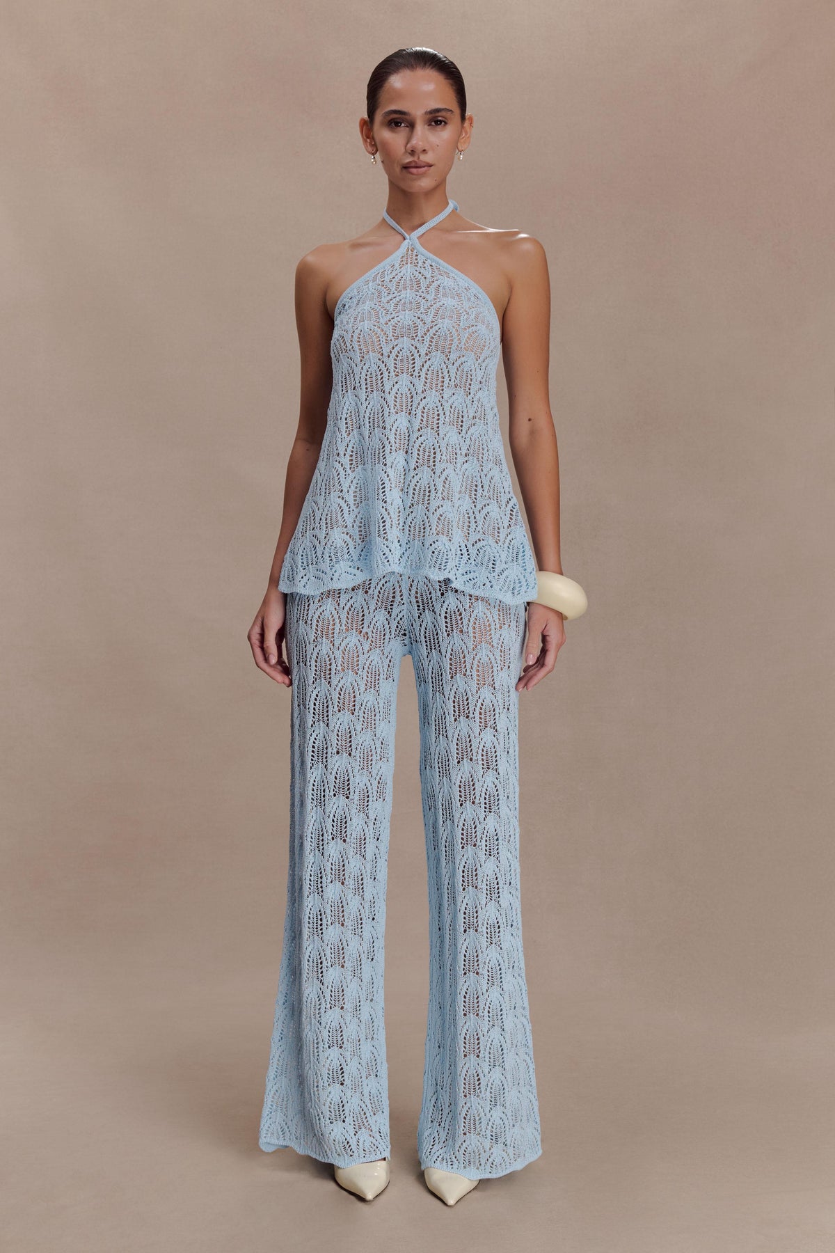 Woman wearing a light blue crochet halter top.