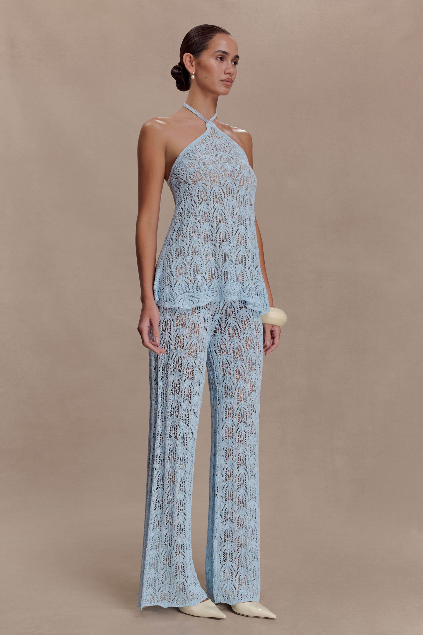 Woman wearing a light blue crochet halter top.
