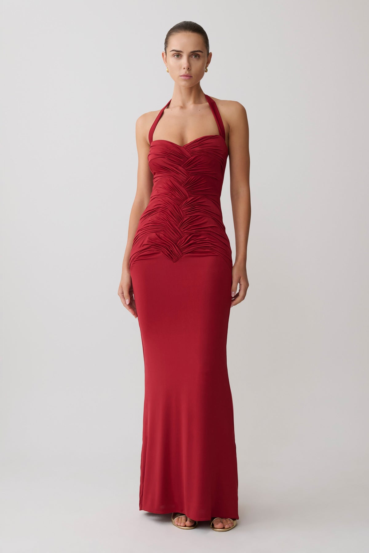 Woman wearing a gathered red halter neck maxi dress.