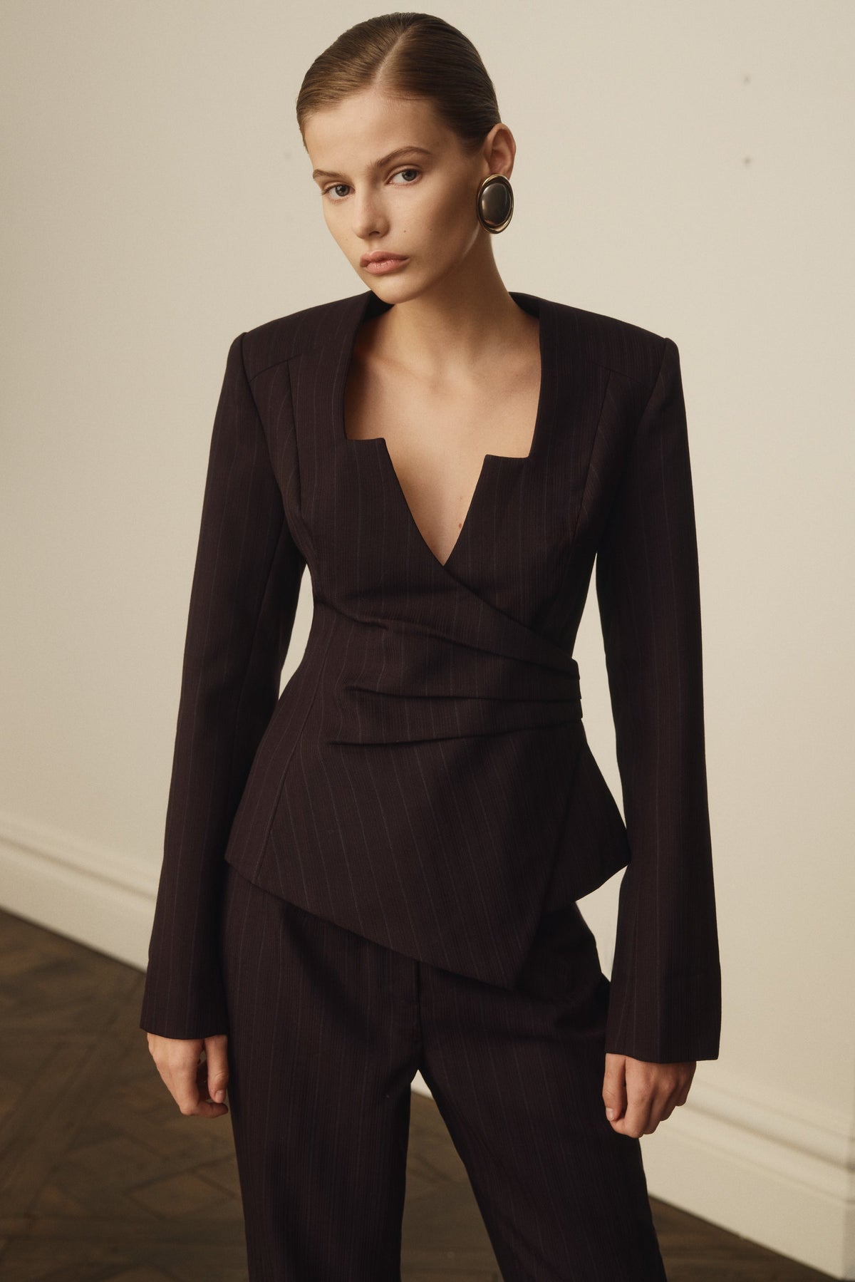 Woman wearing a dark brown suit against a neutral background