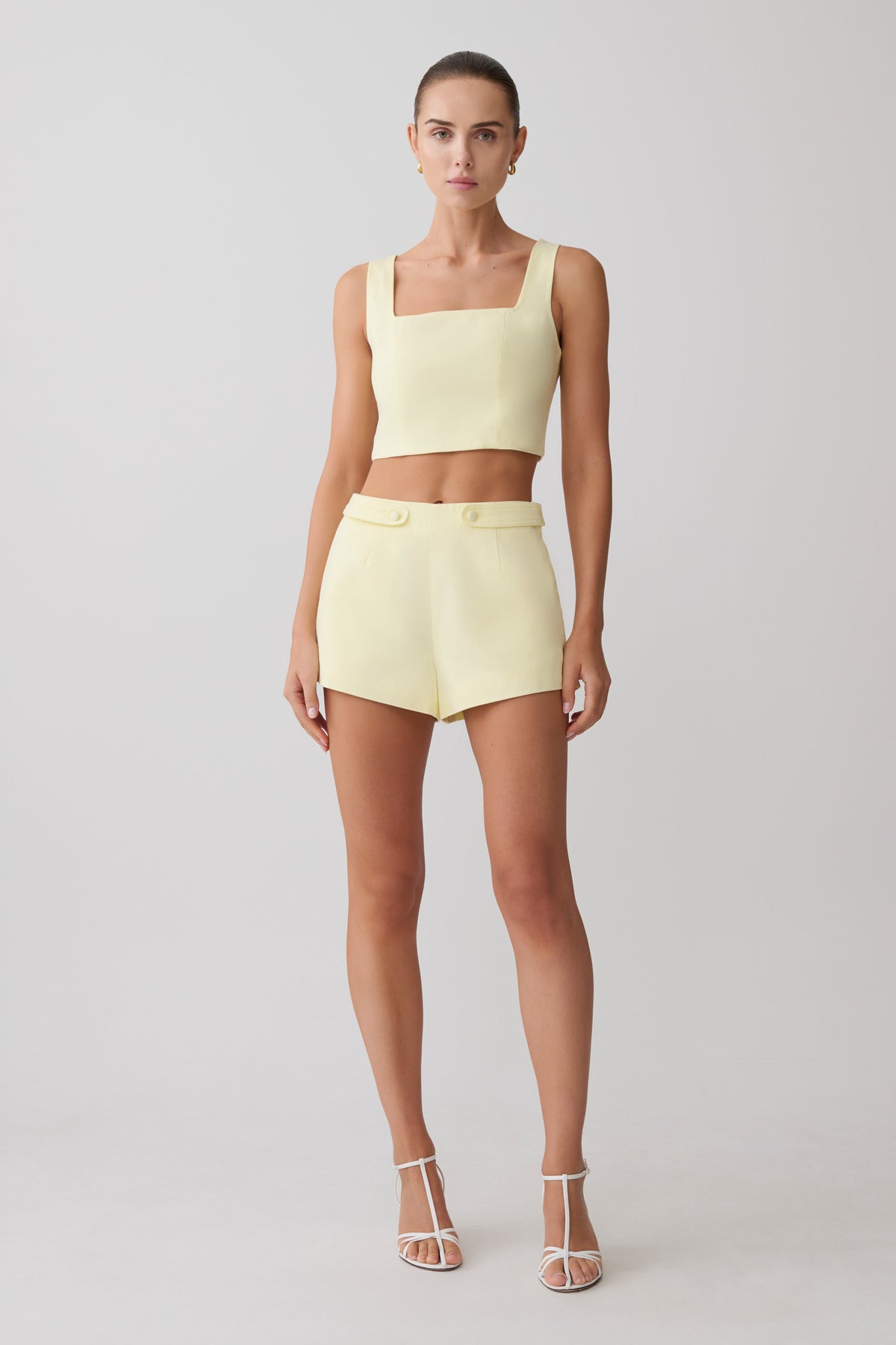 Woman wearing a light yellow sleeveless top and matching shorts.