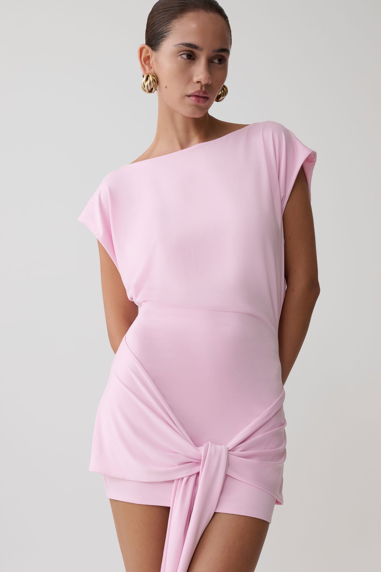 Woman wearing a pink dress with waist tie.