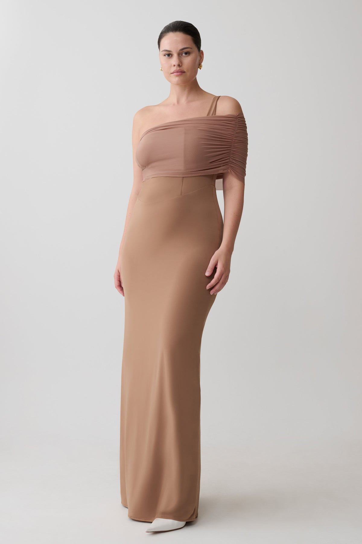 Woman wearing a one-shoulder brown maxi dress.