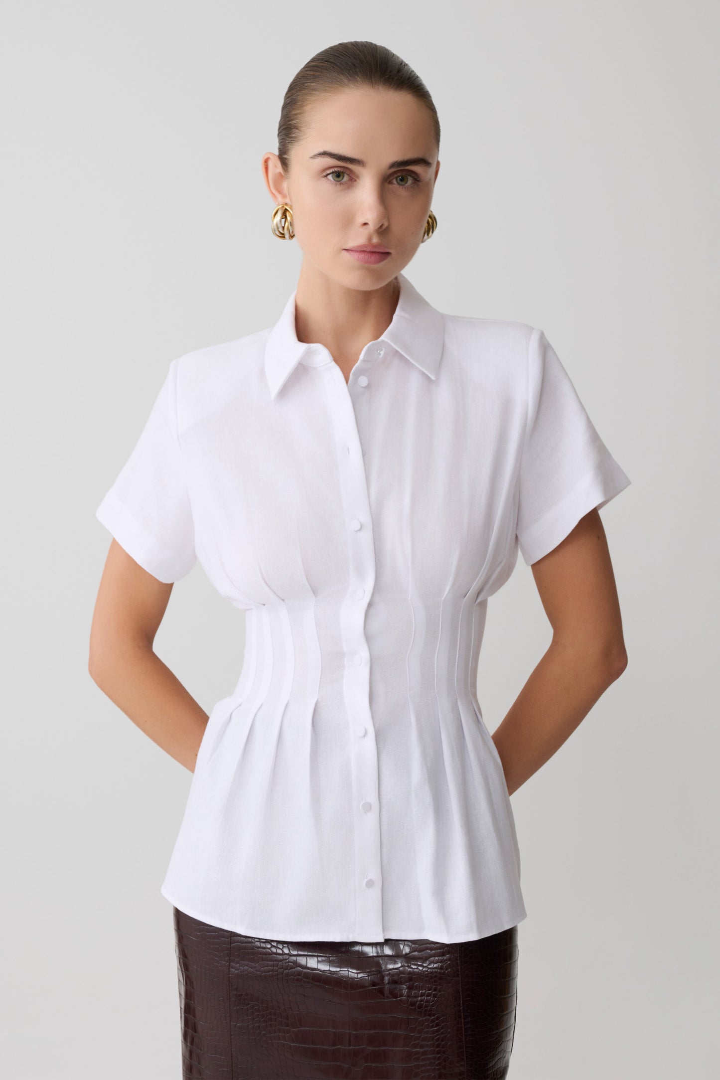 Woman wearing a white blouse with short sleeves on a plain background