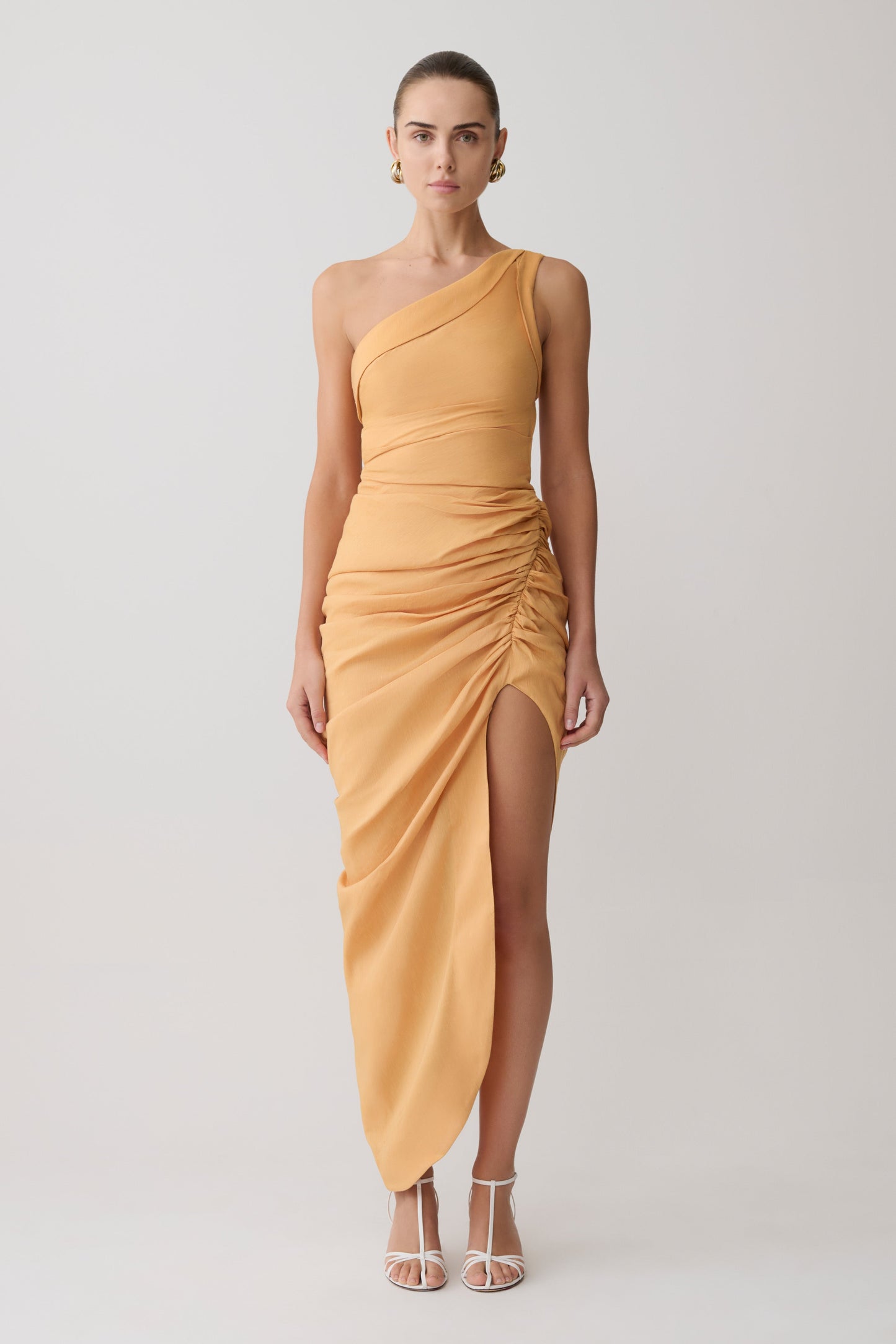 Woman wearing a yellow one-shoulder dress on a white background