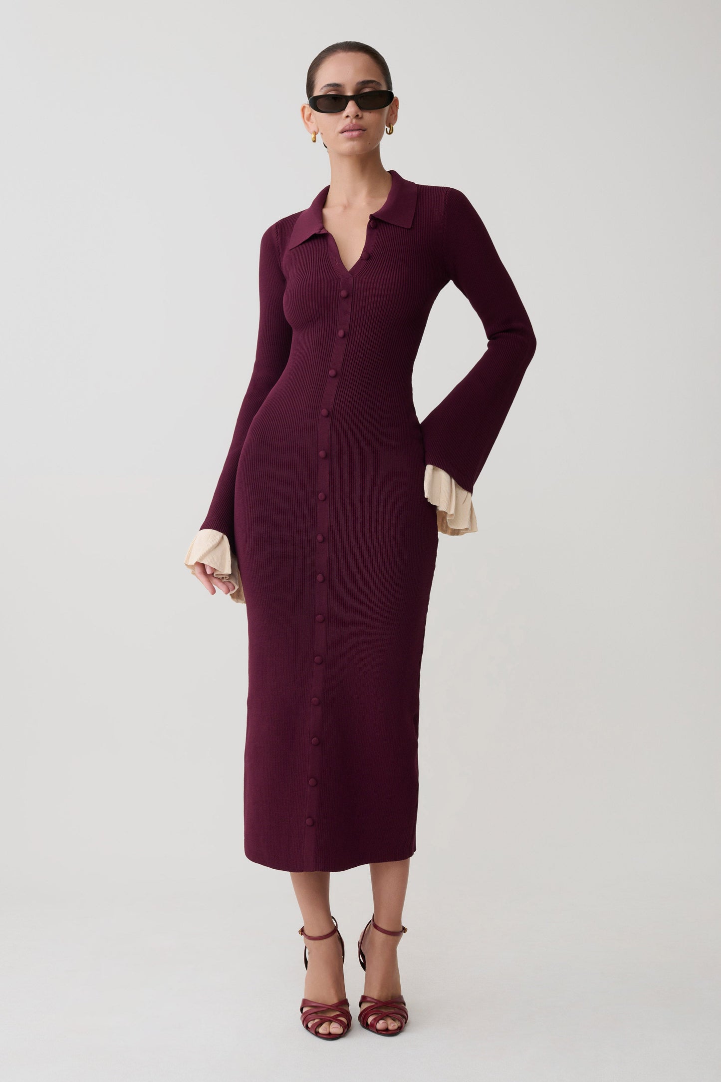 Woman wearing a burgundy dress with long sleeves on a white background