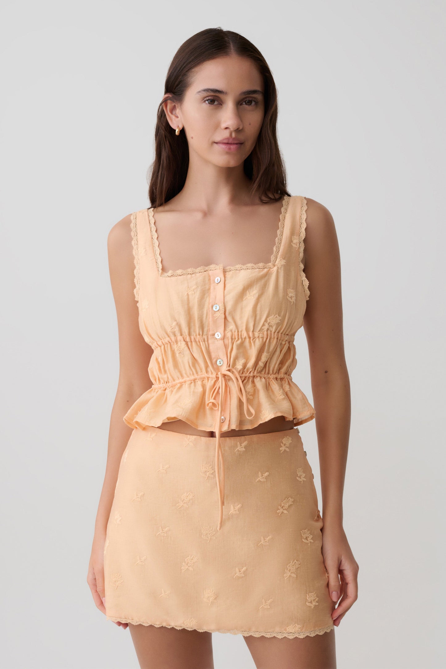 Woman wearing orange embroidered top with matching skirt.