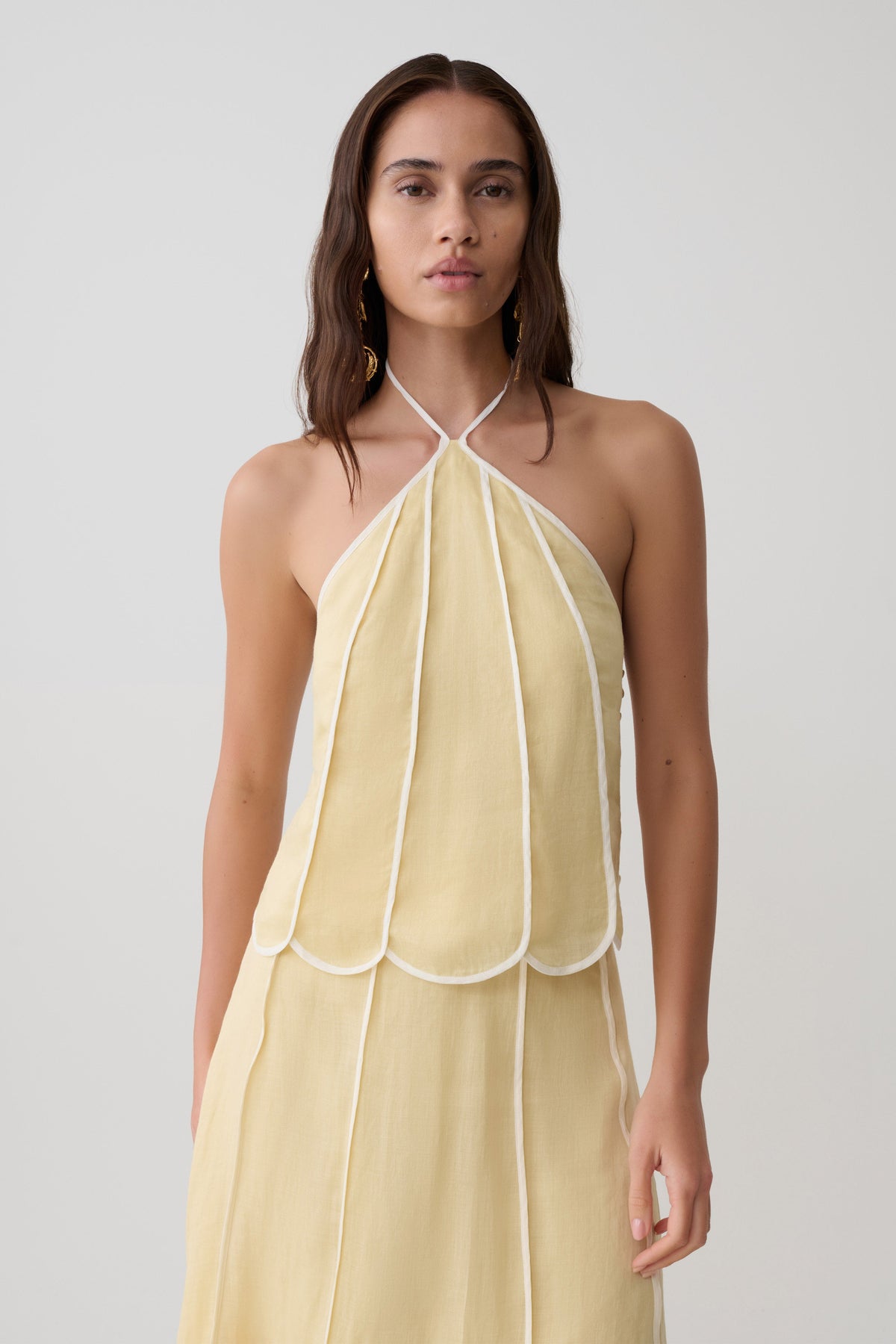 Woman wearing a light yellow panelled halter sleeveless top.