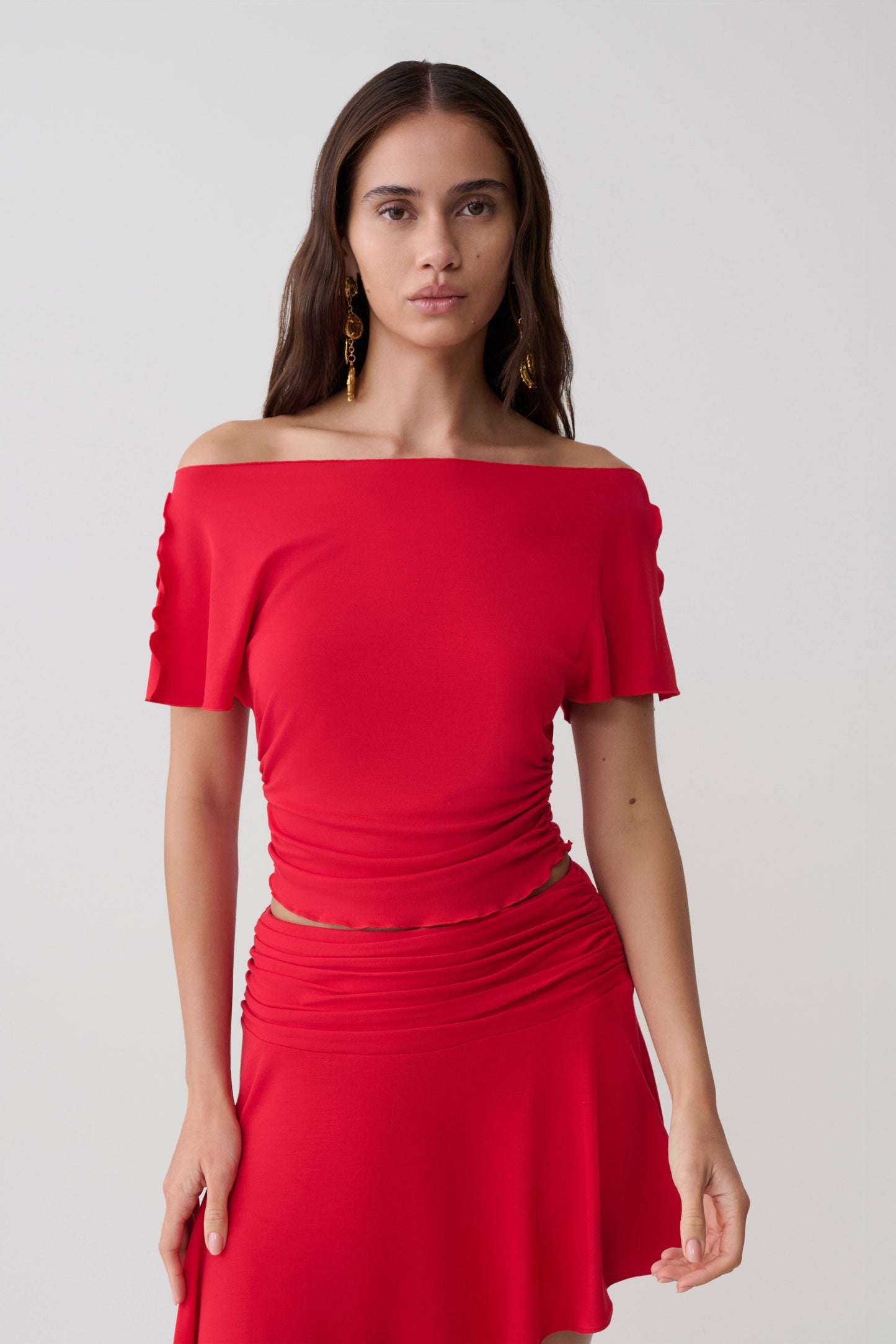 Woman wearing a red short sleeve off-shoulder top.