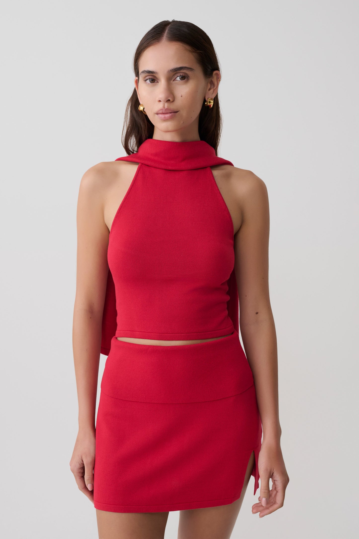 Woman wearing a red halter backless knit top with matching skirt.