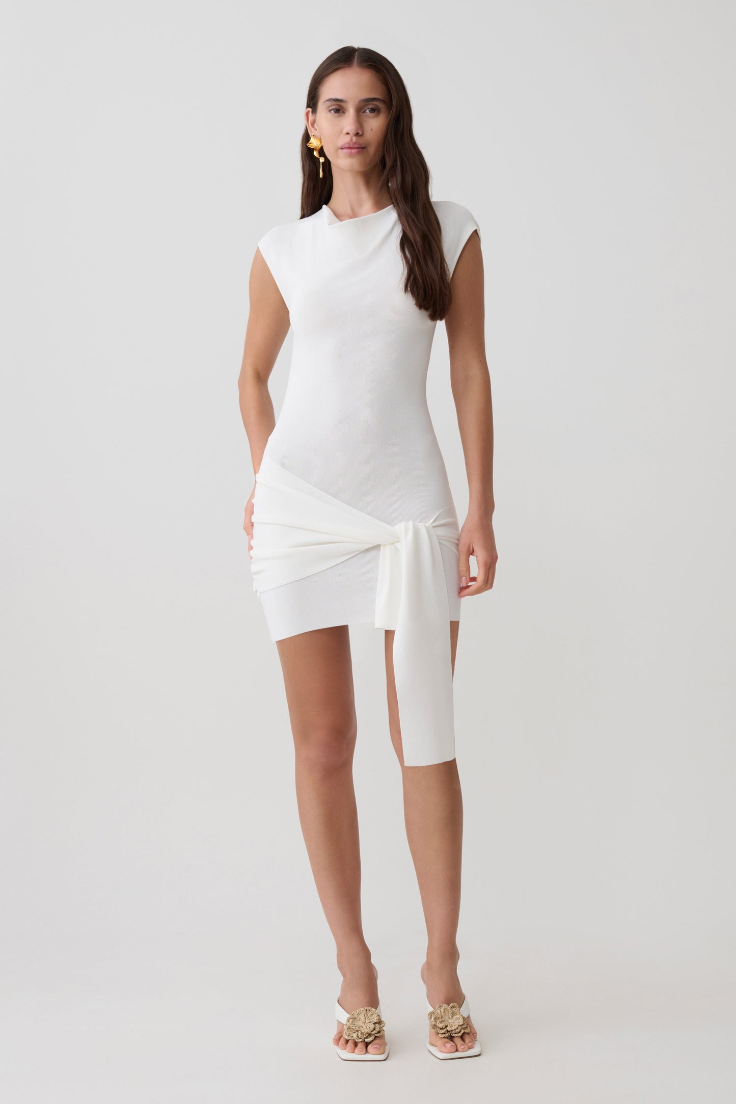 Woman wearing a white knit mini dress with sash.