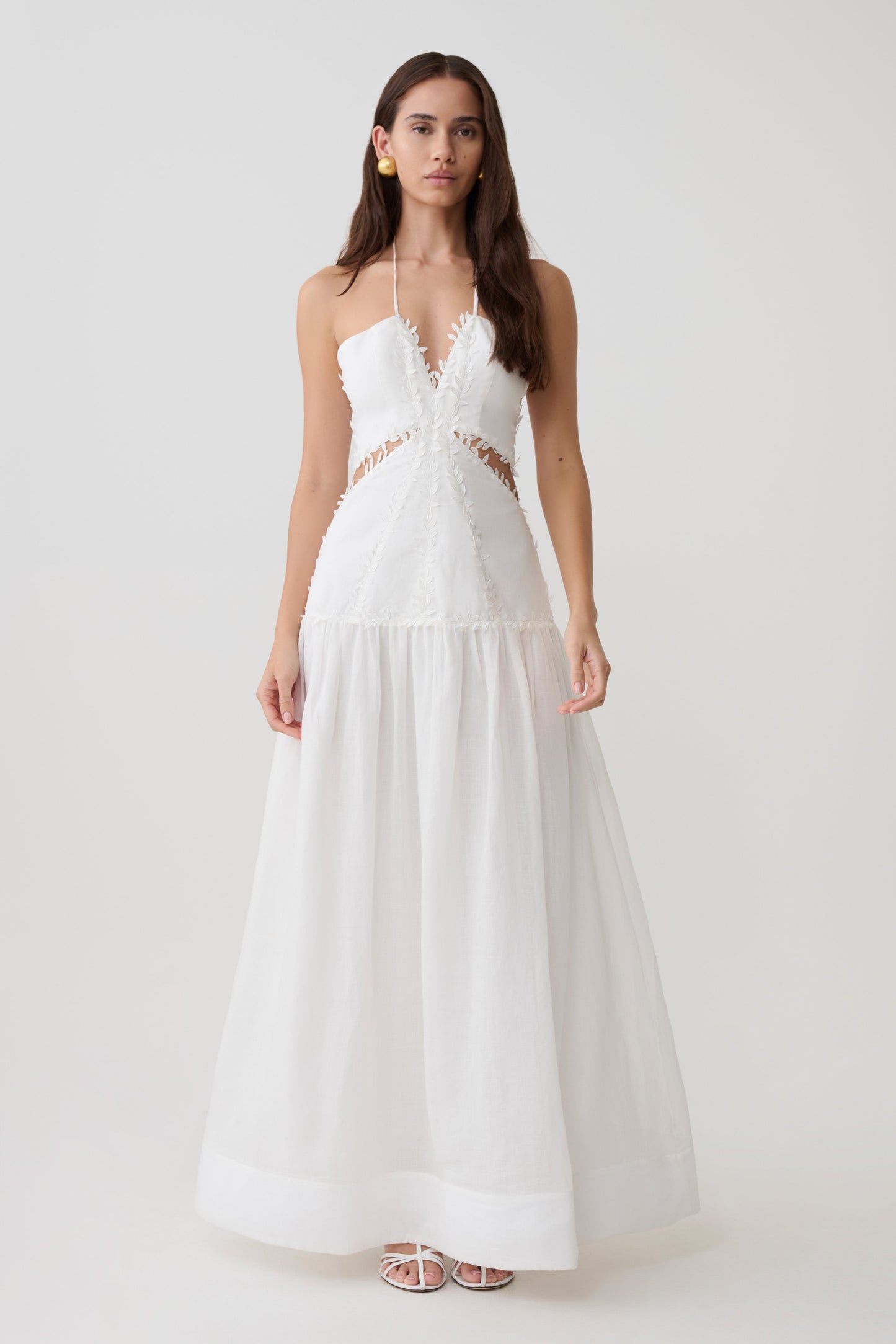 Woman wearing a linen v halter neck with intricate floral details.