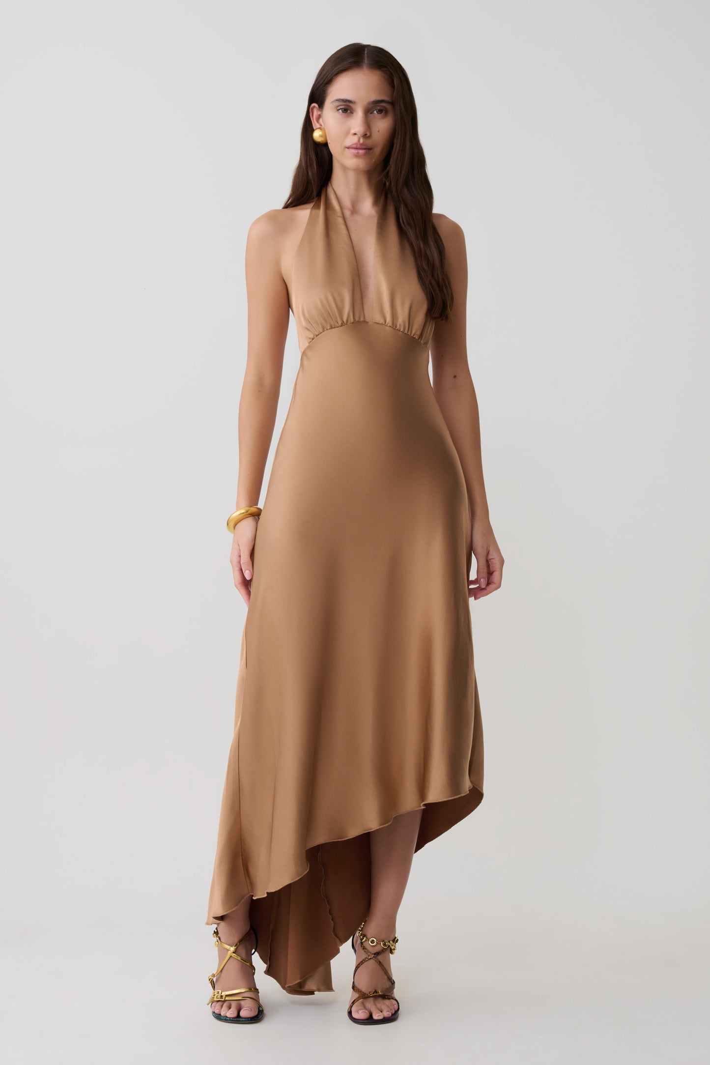 Woman wearing a brown asymmetric hem halter midi dress.