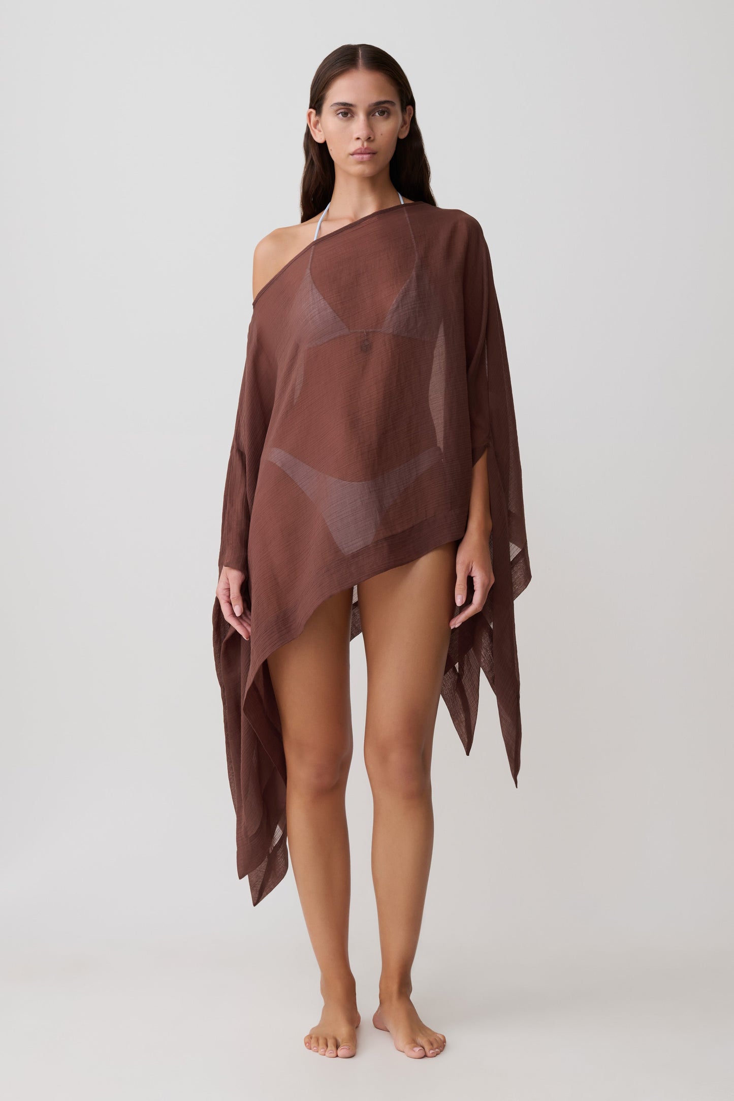 Woman wearing a sheer brown draped asymmetric top.