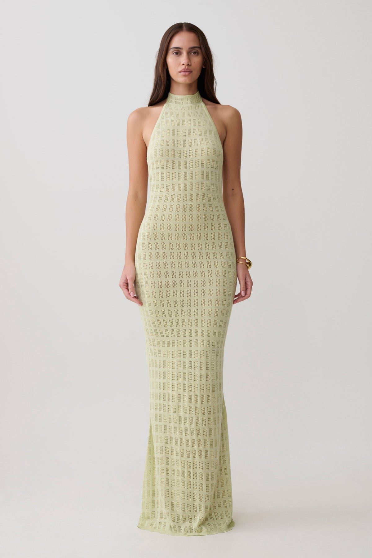 Woman wearing a light green knit halter neck dress.