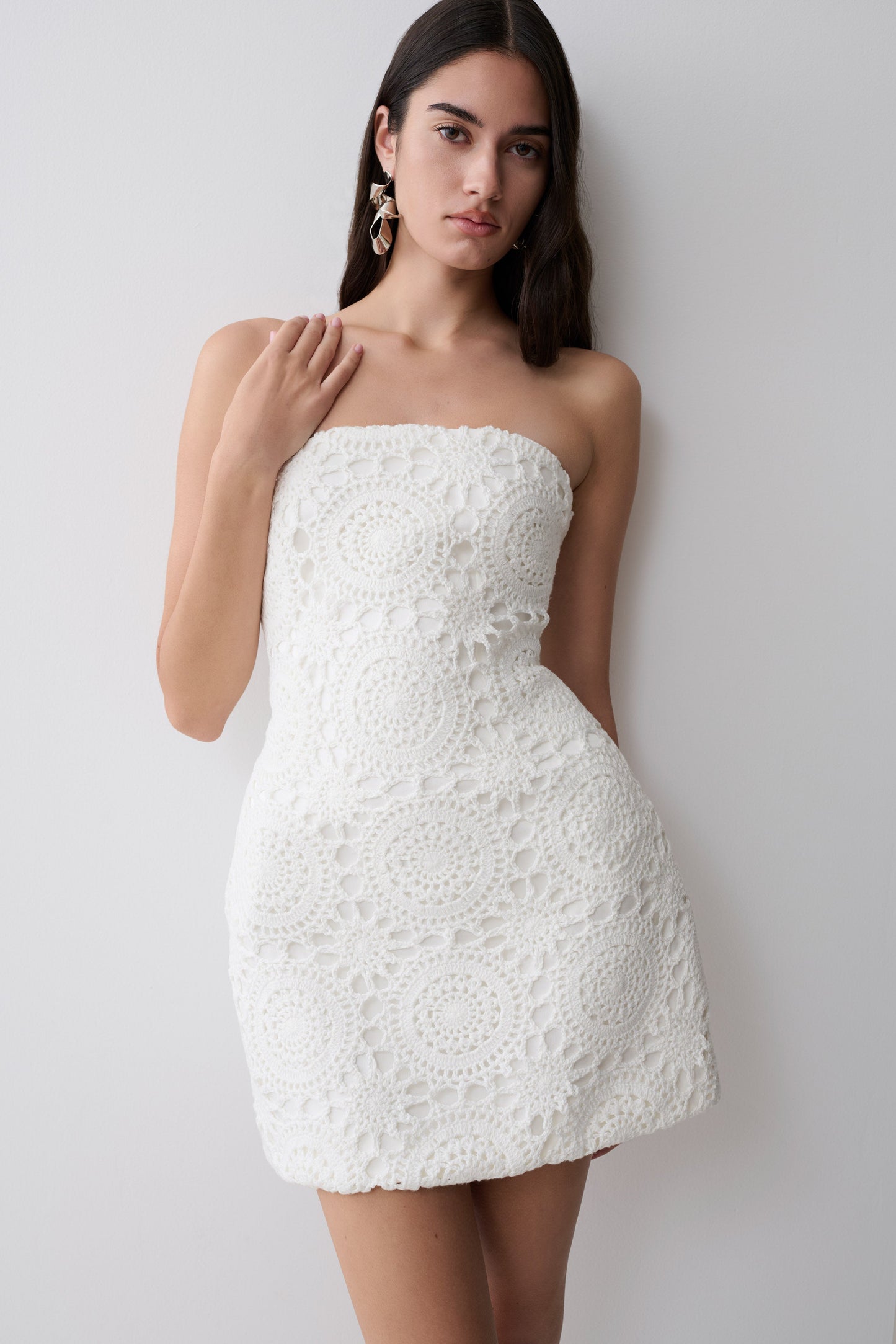 Woman wearing a white strapless crochet mini dress.