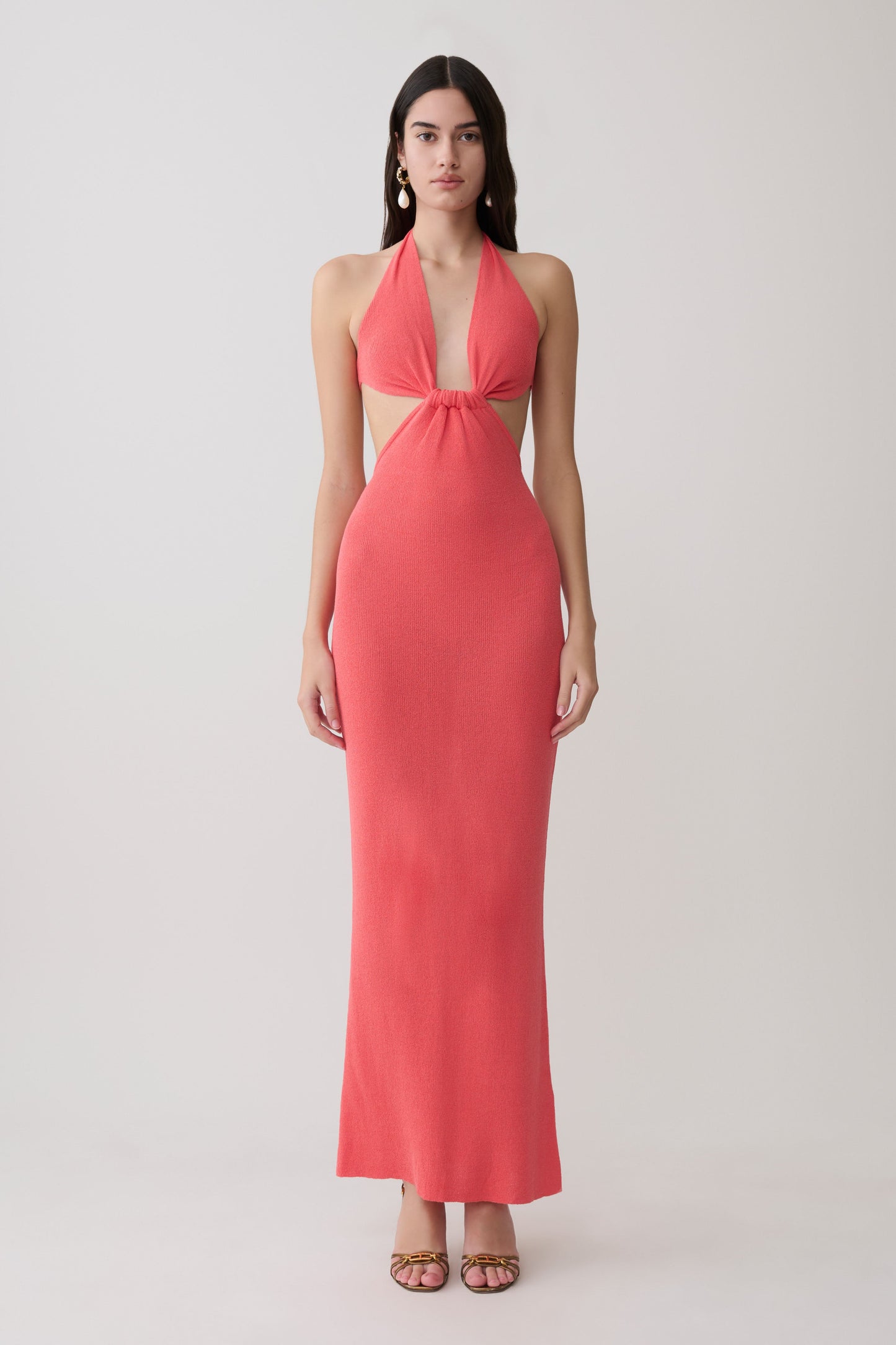 Woman wearing a coral halter knit maxi dress.