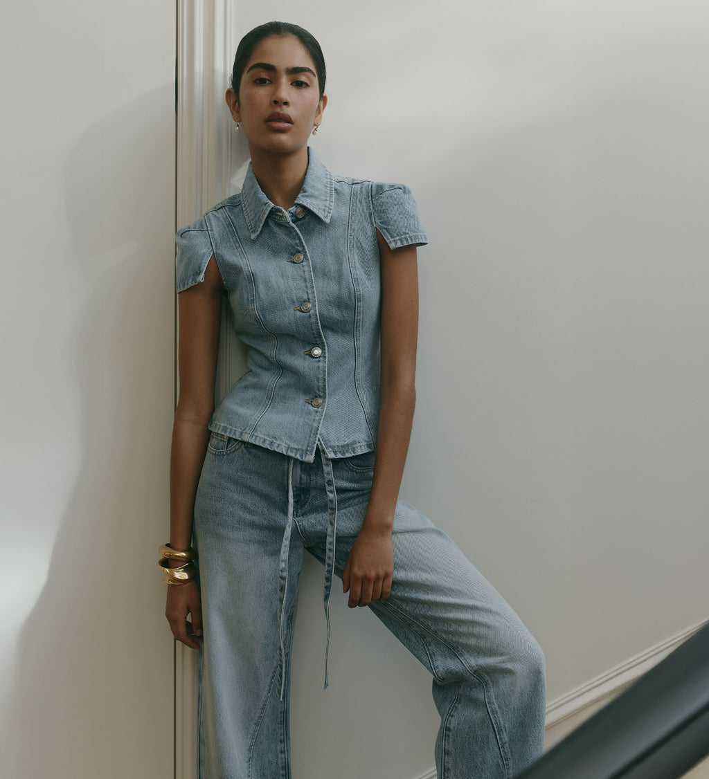 Image of woman wearing denim shortsleeve button up shirt with matching tie up denim jeans
