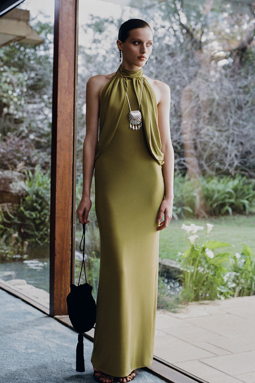 Woman wearing a green halter neck slinky maxi dress.