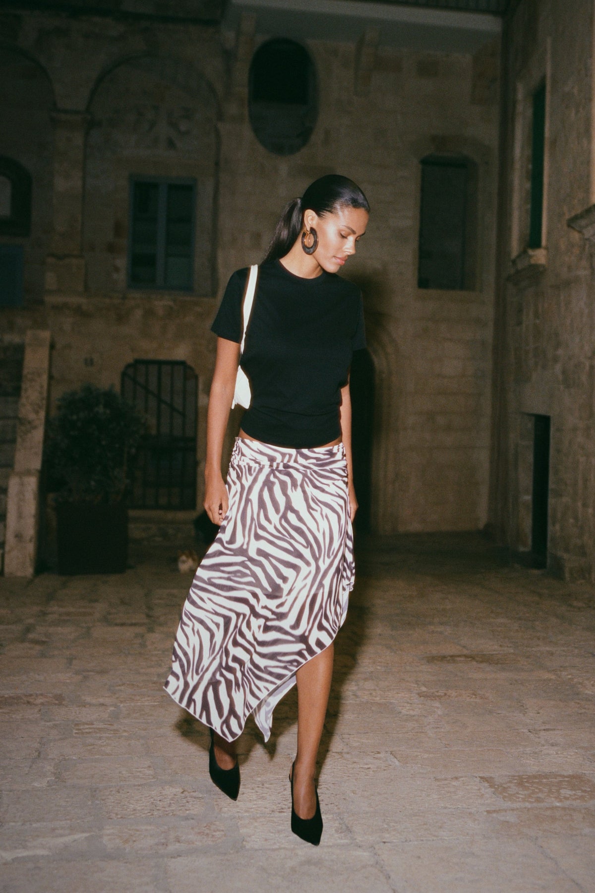 Woman in black top and zebra print chiffon midi skirt.