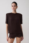 Woman wearing a dark brown shoulder pad short sleeve satin top with matching lace shorts.