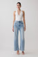 Woman wearing a white slinky halter bodysuit with blue jeans.