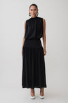 Woman wearing a black sleeveless drop waist gathered midaxi dress.