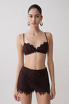 Woman wearing a dark brown lace bralette with matching lace shorts. 