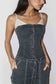 A woman wearing a dark gray denim corset-style camisole top with front lace-up detailing and matching dark denim bottoms, shown against a plain light background.
