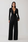 Woman wearing black cowl long sleeve slinky bodysuit, with black pants.