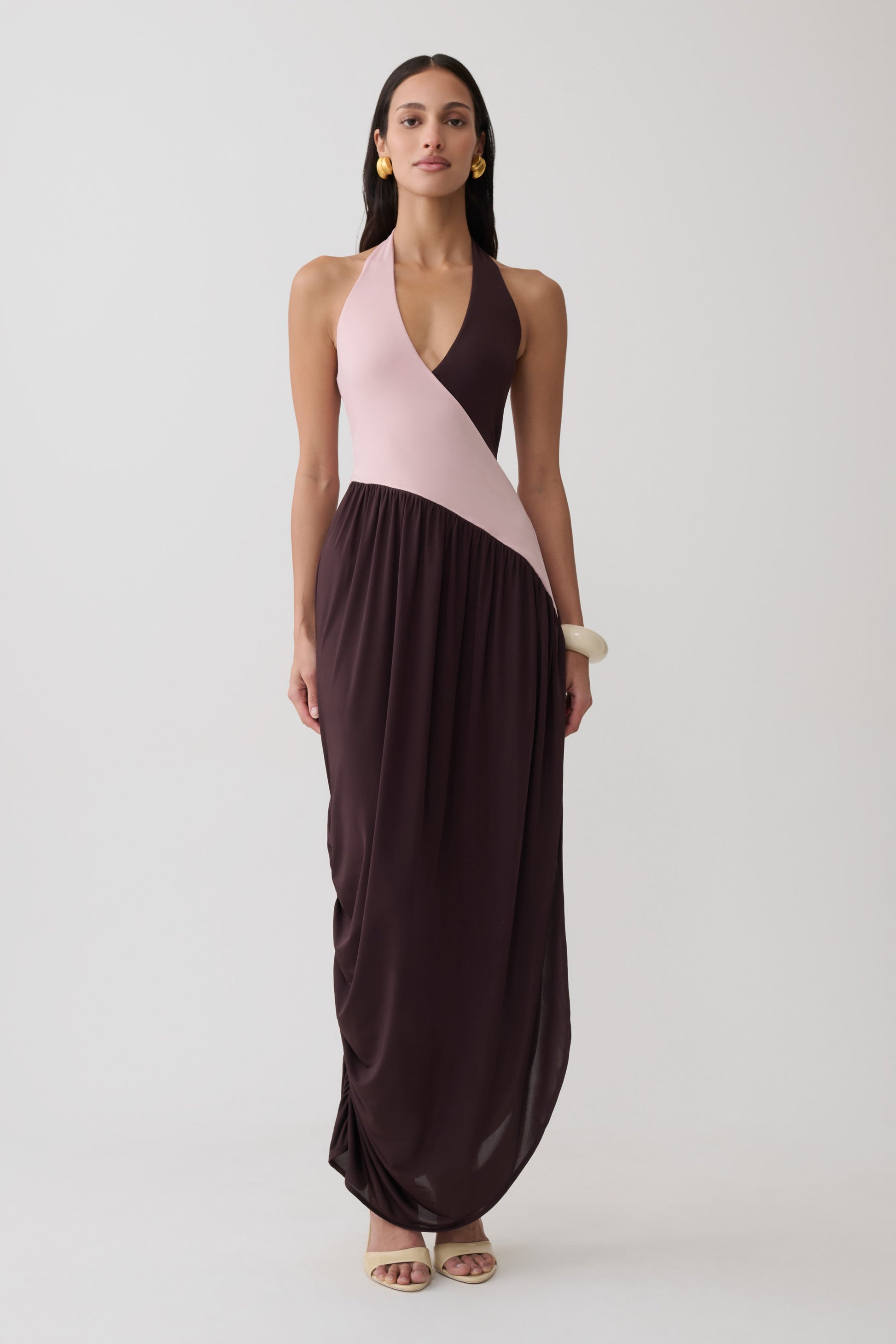 Woman wearing a pink and brown halter gathered maxi dress.