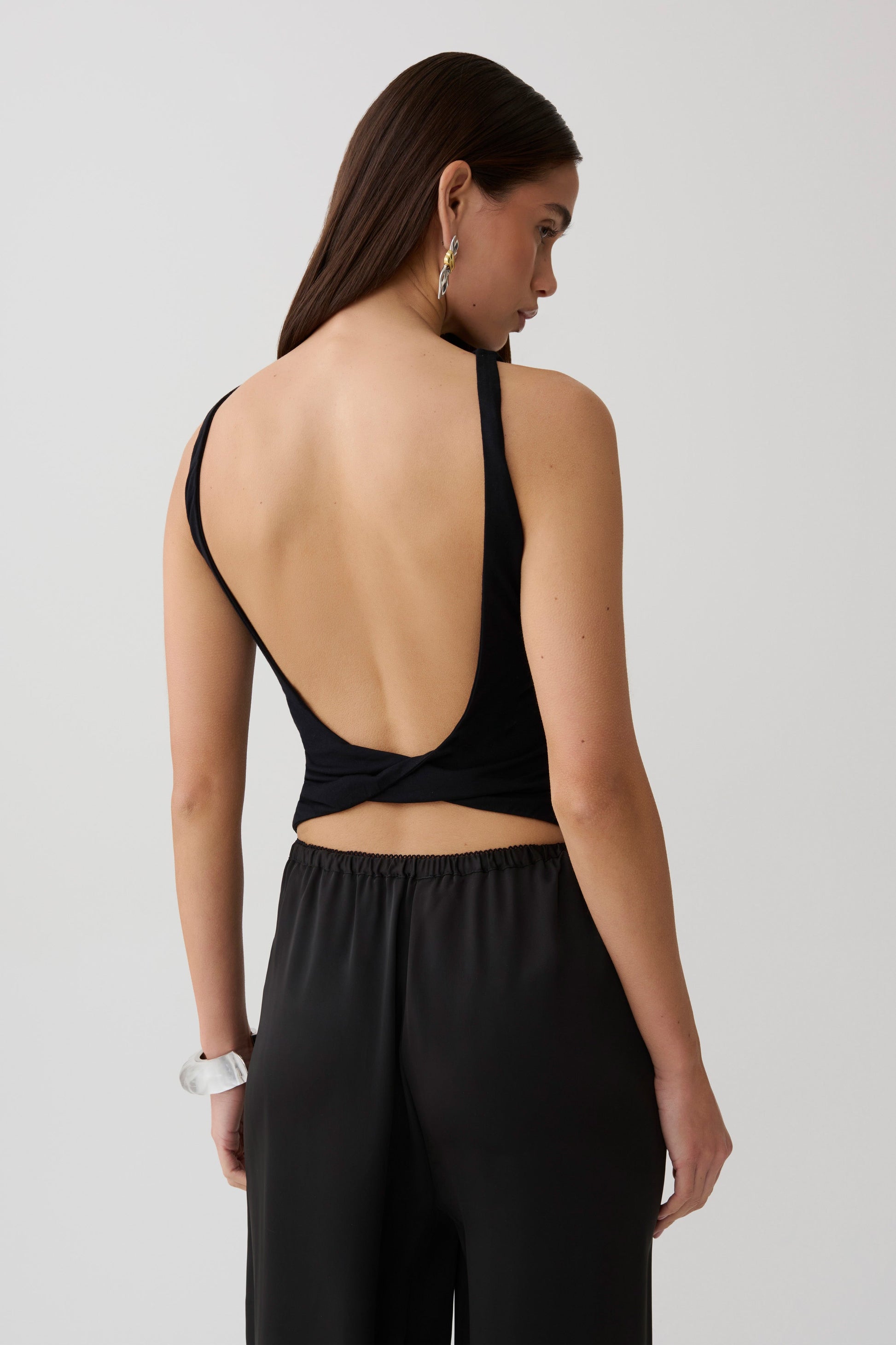 Woman wearing black backless twist top.