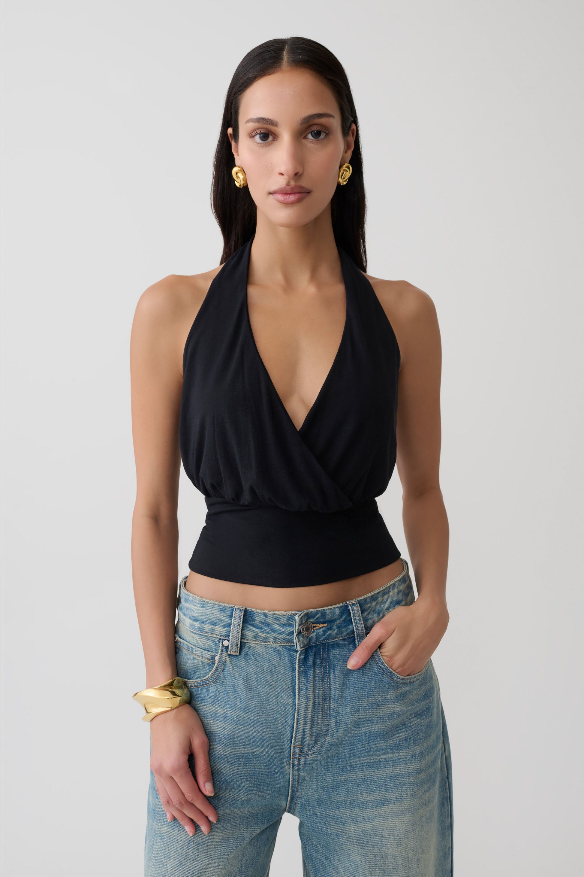 Woman wearing a black draped halter top. 