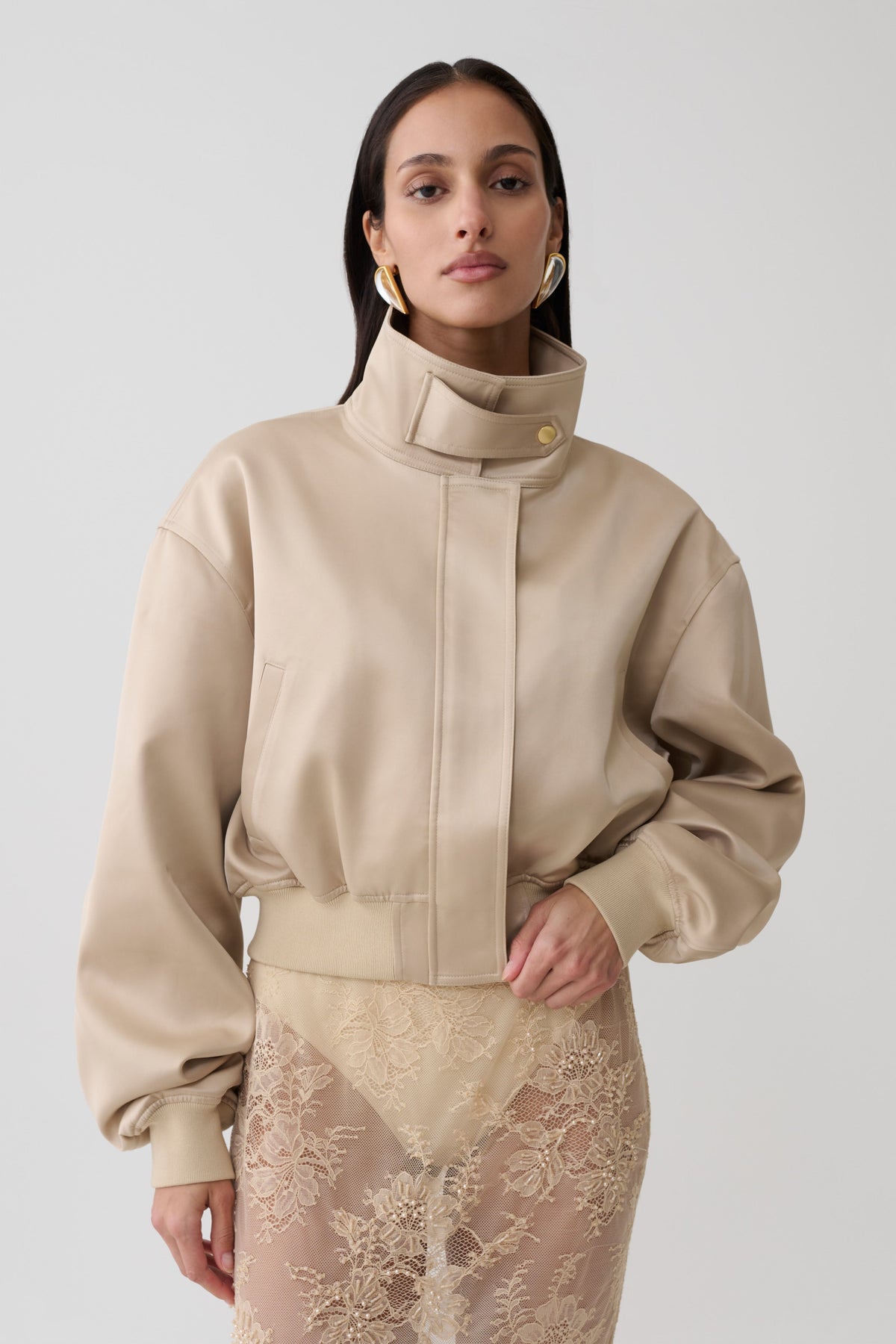 Woman wearing a gold satin bomber jacket.
