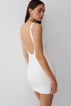 Woman wearing a white backless twist mini dress.