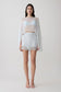 Woman wearing light blue bralette with chiffon cape with matching lace and satin mini skirt.