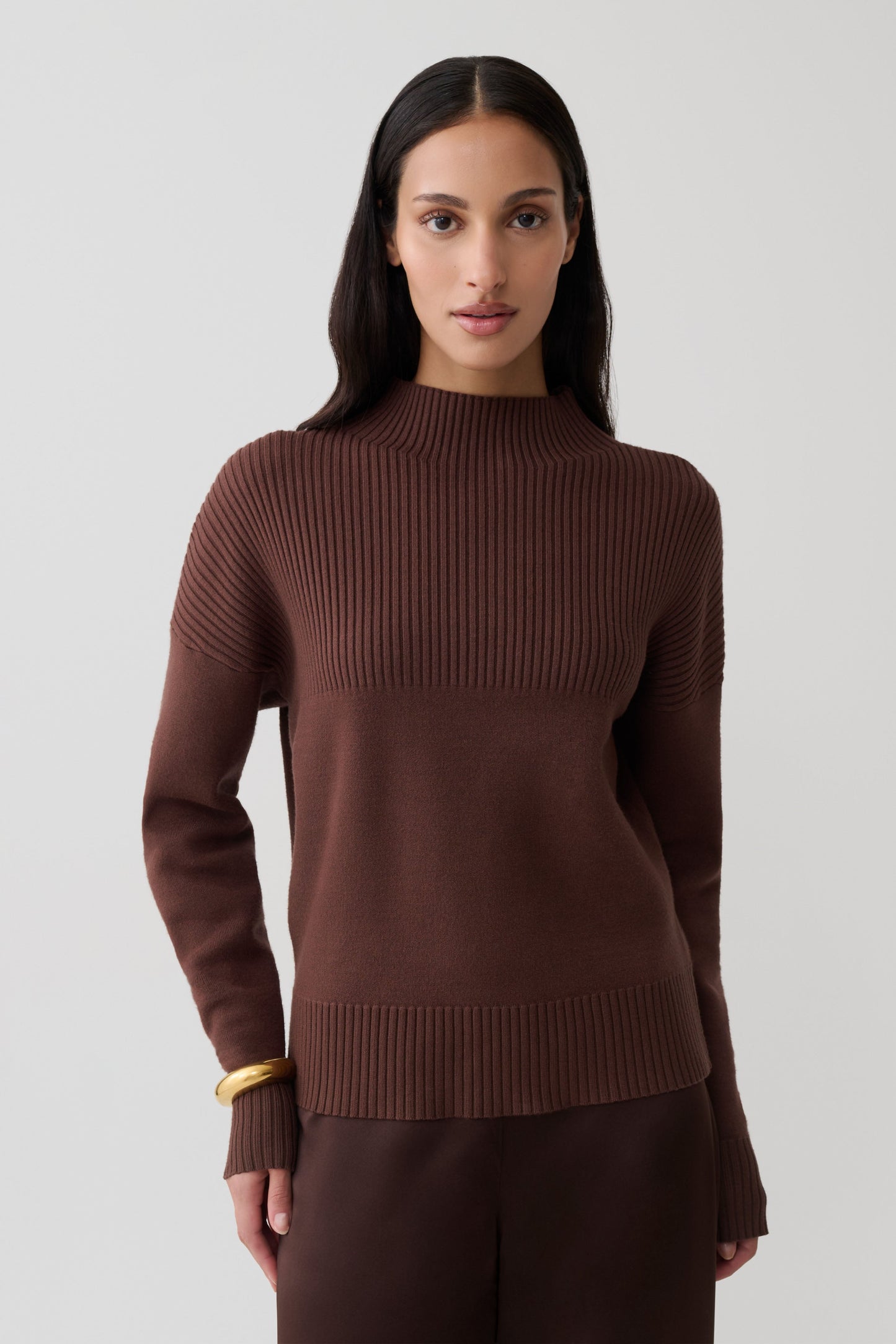 Woman wearing a brown ribbed high neck jumper.