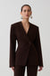 Woman wearing dark brown drop shoulder suiting blazer.