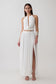 Woman wearing a white halter neck top with hardware and a matching bubble hem midi skirt.